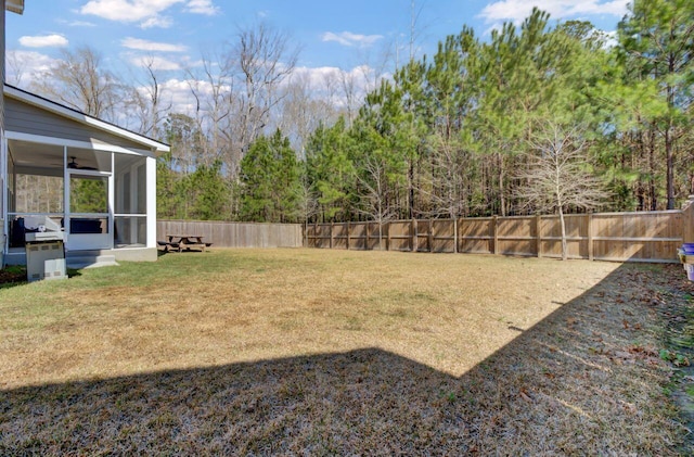 view of yard featuring a ceiling fan, a fenced backyard, and a sunroom