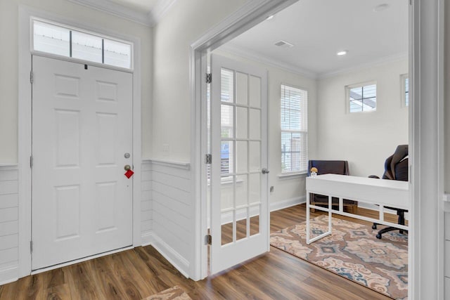 foyer entrance with a wainscoted wall, visible vents, wood finished floors, and crown molding