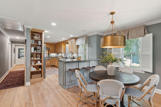 dining space featuring baseboards, ornamental molding, light wood-style flooring, and recessed lighting