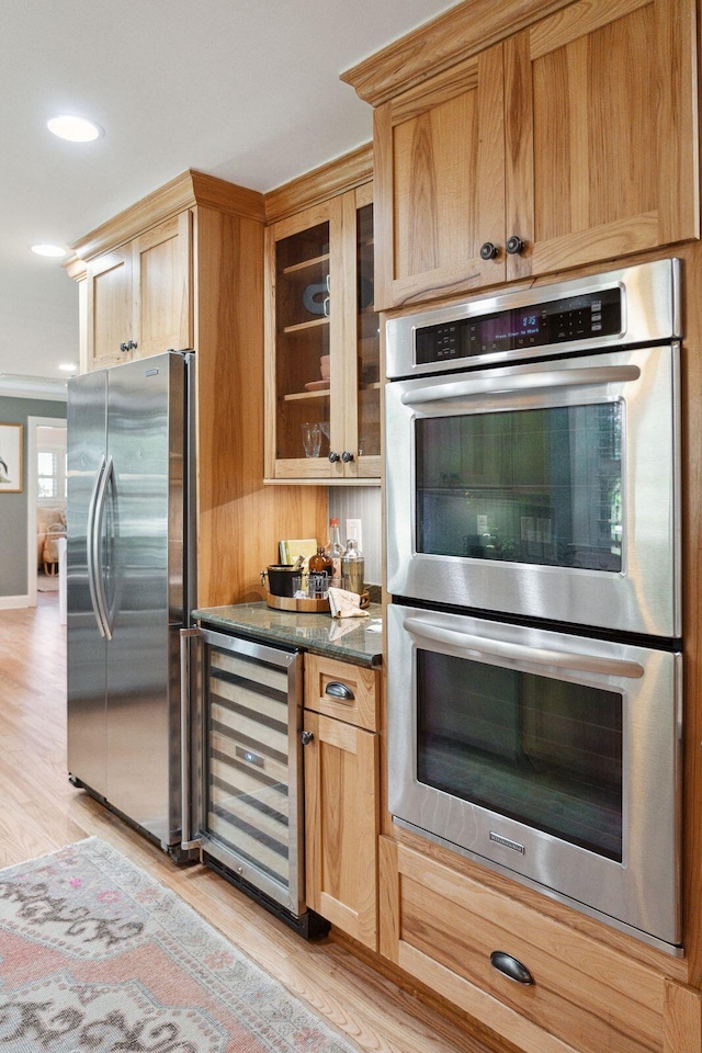 kitchen featuring beverage cooler, light wood-type flooring, glass insert cabinets, and stainless steel appliances