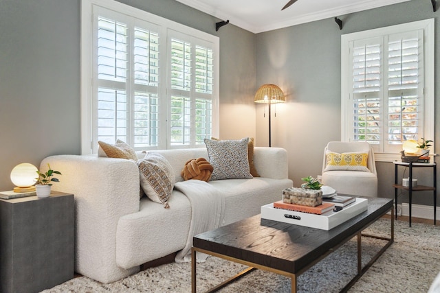 living room with crown molding, baseboards, plenty of natural light, and a ceiling fan
