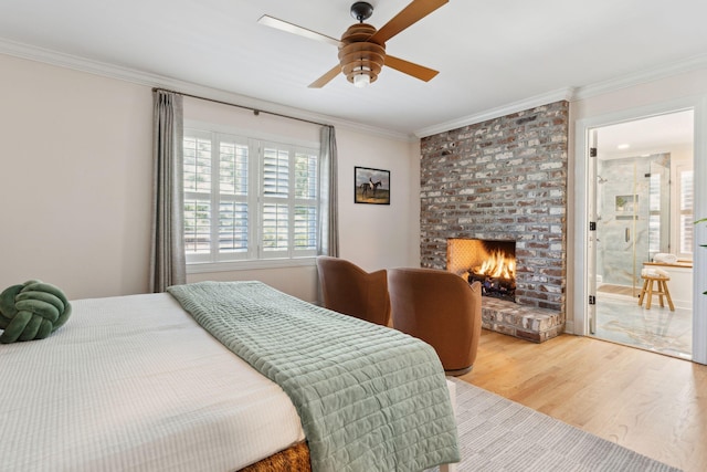 bedroom with crown molding, a brick fireplace, wood finished floors, a ceiling fan, and ensuite bath