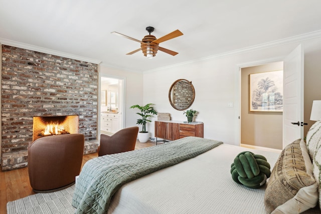bedroom featuring ceiling fan, crown molding, a fireplace, wood finished floors, and ensuite bath