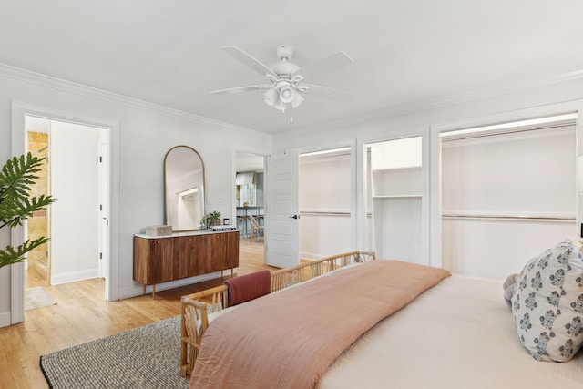 bedroom with ornamental molding, multiple closets, baseboards, ceiling fan, and light wood-type flooring