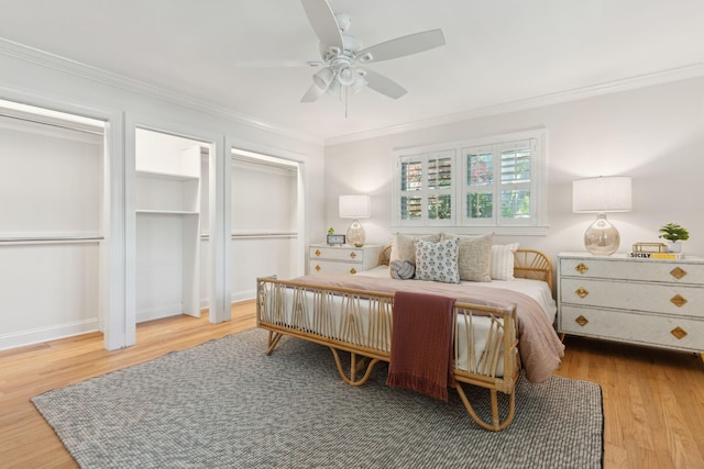bedroom featuring ceiling fan, multiple closets, ornamental molding, and wood finished floors