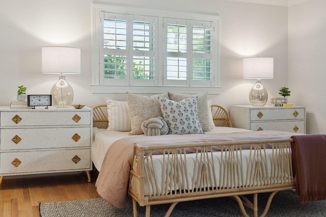 bedroom with ornamental molding, wood finished floors, and multiple windows