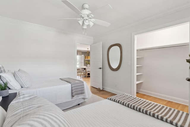 bedroom with baseboards, a ceiling fan, light wood-style floors, and crown molding