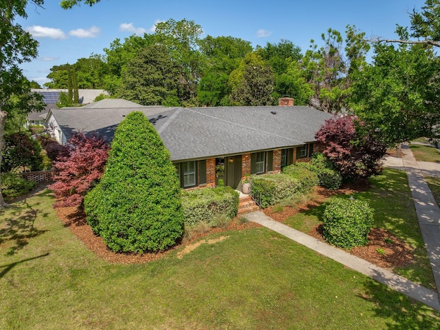 single story home featuring a shingled roof, a front lawn, and a chimney