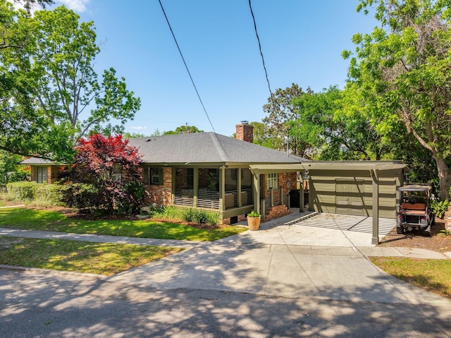 single story home featuring stone siding, a front yard, a chimney, driveway, and a carport