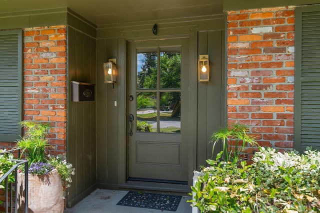 view of exterior entry with board and batten siding and brick siding