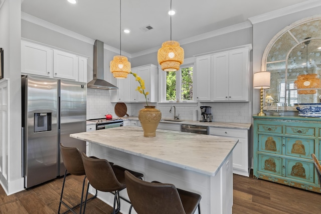 129 Martins Point Dr, Wando, SC 29492 - kitchen featuring appliances with stainless steel finishes, wall chimney exhaust hood, plenty of natural light, crown molding, and white cabinetry