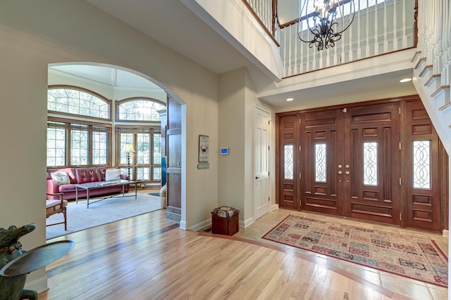 entryway featuring a towering ceiling, baseboards, arched walkways, and wood finished floors