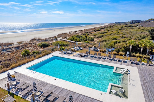 community pool featuring a patio, a water view, and a view of the beach