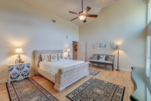 bedroom with high vaulted ceiling, a ceiling fan, visible vents, baseboards, and light wood finished floors