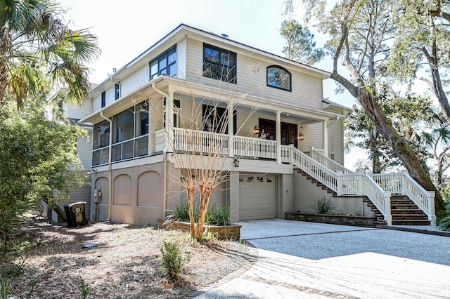 view of front facade with a porch, driveway, an attached garage, and stairs