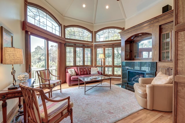 living area with light wood finished floors, crown molding, a fireplace, high vaulted ceiling, and recessed lighting