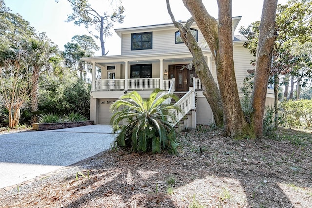 coastal home with a porch, driveway, stairway, and an attached garage