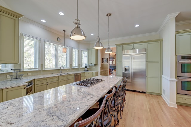 kitchen featuring a breakfast bar area, appliances with stainless steel finishes, crown molding, light wood-style floors, and a sink