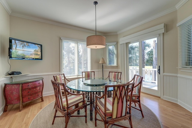 dining space with ornamental molding, light wood finished floors, and wainscoting