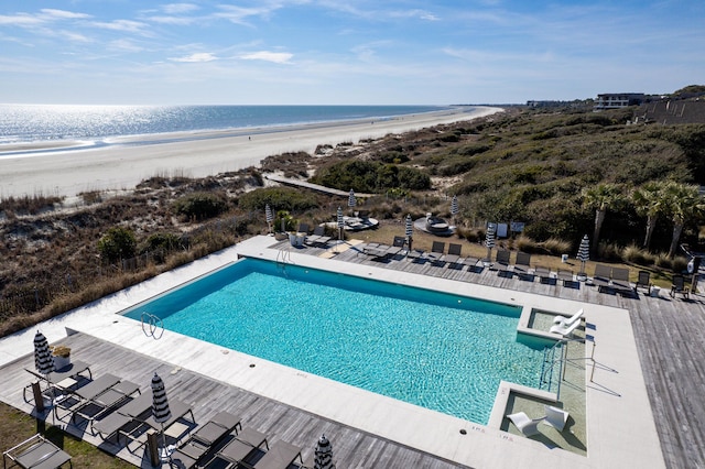 community pool featuring a view of the beach, a water view, and a patio