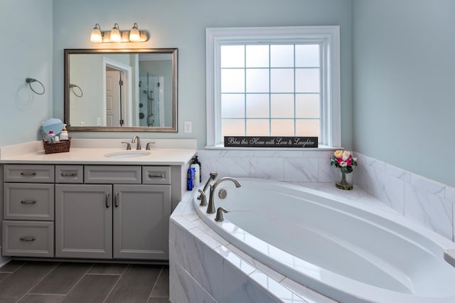 bathroom with tiled tub and vanity