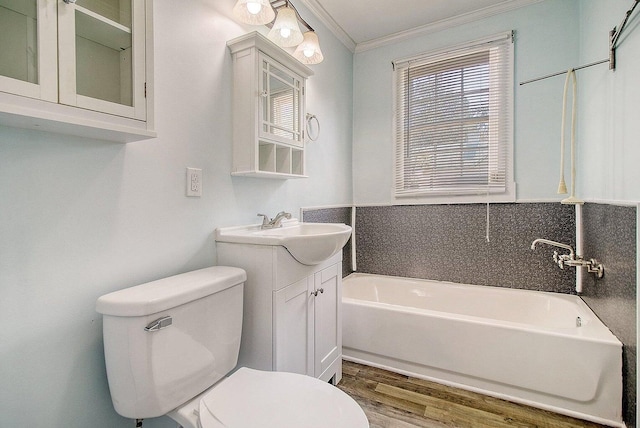 bathroom featuring a washtub, wood-type flooring, vanity, ornamental molding, and toilet