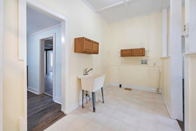 washroom featuring ornamental molding, hookup for a washing machine, light hardwood / wood-style flooring, and cabinets