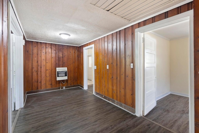 spare room featuring heating unit, wooden walls, dark hardwood / wood-style floors, and crown molding