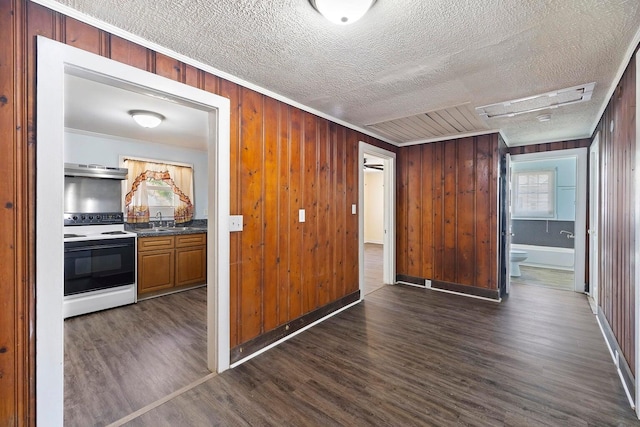 kitchen with electric stove, wooden walls, and dark hardwood / wood-style flooring