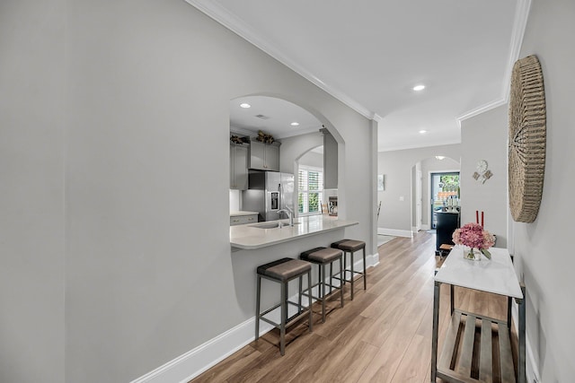 1173 Triple Crown Ct, Mount Pleasant, SC 29429 - kitchen with light countertops, a sink, a kitchen bar, stainless steel fridge, and arched walkways