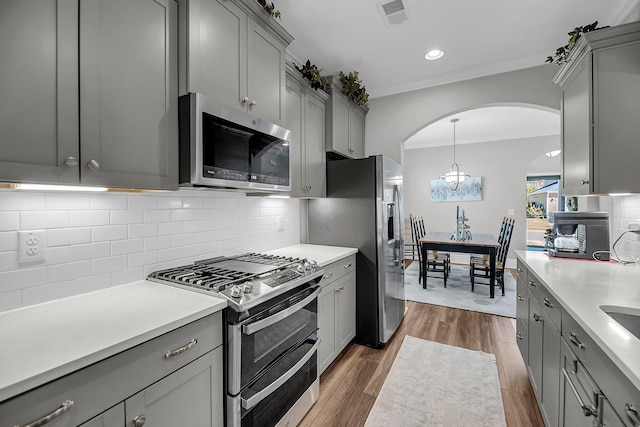 1173 Triple Crown Ct, Mount Pleasant, SC 29429 - kitchen with crown molding, gray cabinetry, stainless steel appliances, visible vents, and arched walkways