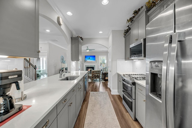 1173 Triple Crown Ct, Mount Pleasant, SC 29429 - kitchen with a lit fireplace, a sink, a ceiling fan, appliances with stainless steel finishes, and gray cabinetry