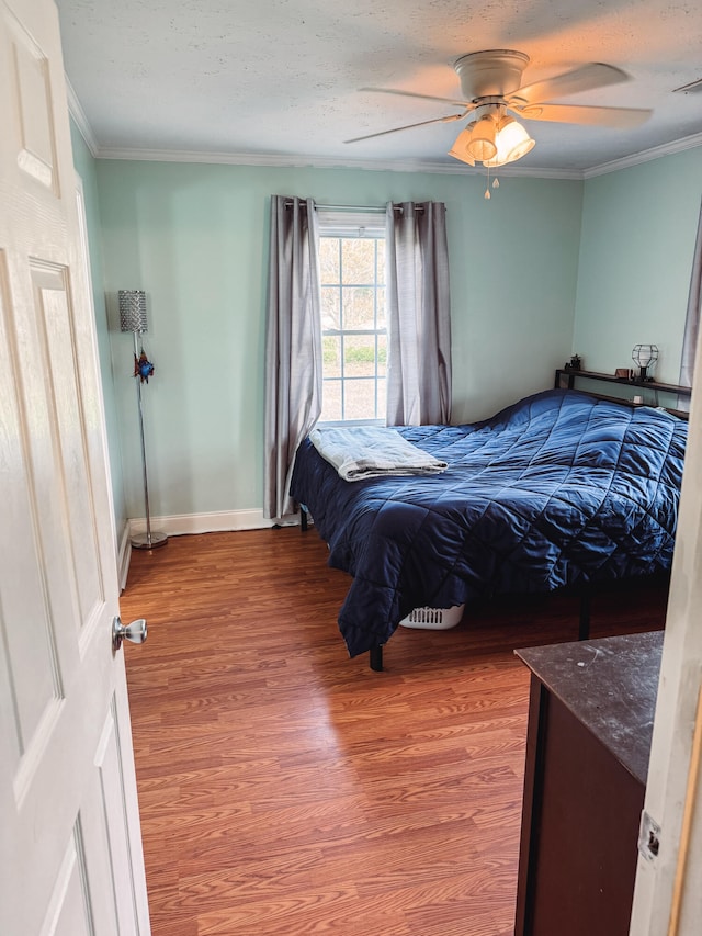 bedroom featuring a textured ceiling, ceiling fan, hardwood / wood-style flooring, and crown molding