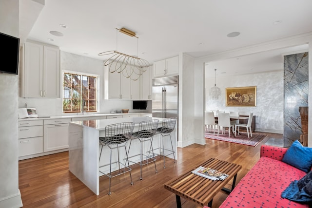 kitchen with hanging light fixtures, hardwood / wood-style floors, a center island, and white cabinets