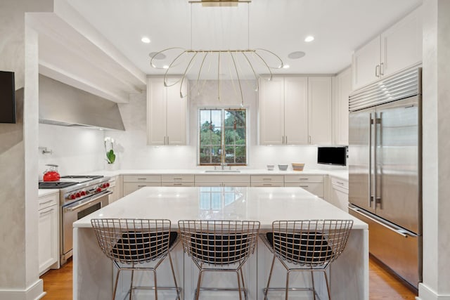 kitchen featuring a center island, white cabinets, premium appliances, and a breakfast bar