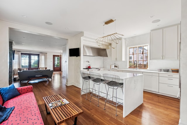 kitchen featuring a center island, hardwood / wood-style flooring, a kitchen breakfast bar, pendant lighting, and white cabinets