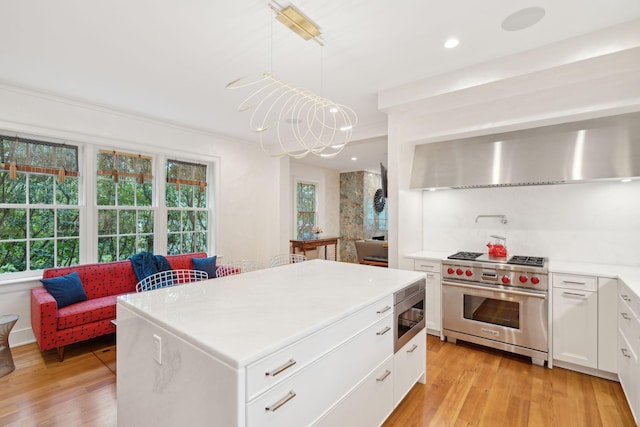 kitchen featuring a center island, light hardwood / wood-style flooring, hanging light fixtures, appliances with stainless steel finishes, and white cabinets