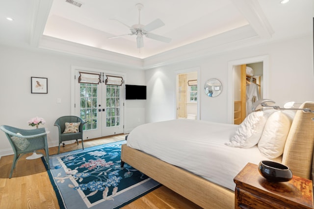 bedroom with french doors, connected bathroom, a raised ceiling, ceiling fan, and access to exterior