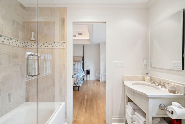 bathroom with enclosed tub / shower combo, wood-type flooring, ornamental molding, and vanity