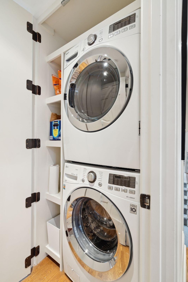 laundry room with stacked washer and clothes dryer and light wood-type flooring