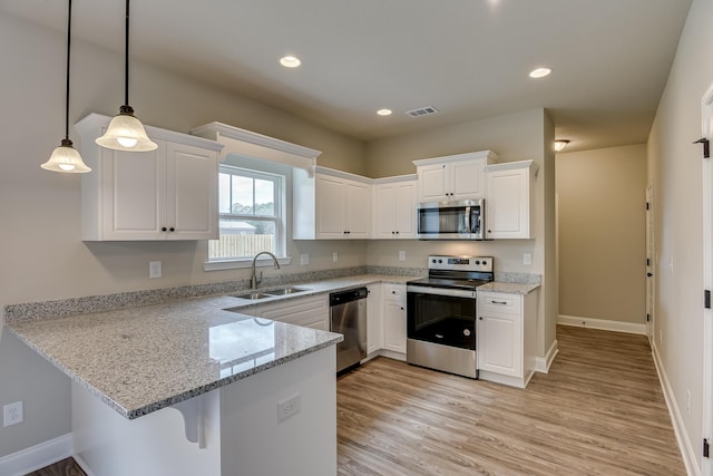 kitchen with pendant lighting, sink, appliances with stainless steel finishes, white cabinetry, and kitchen peninsula