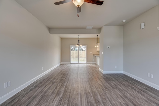 unfurnished living room featuring ceiling fan with notable chandelier and dark wood-type flooring