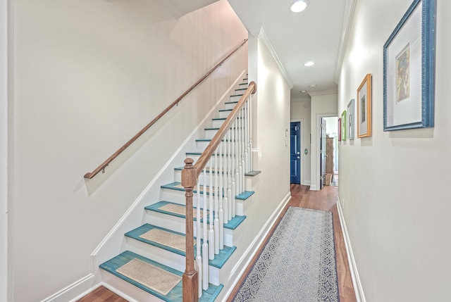 stairway with crown molding and hardwood / wood-style flooring