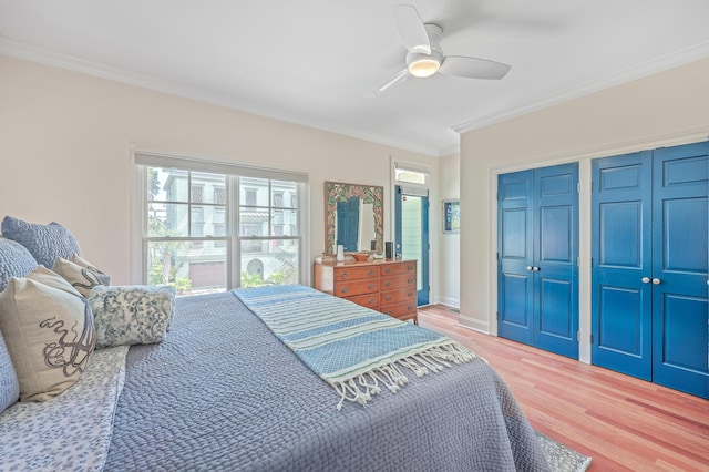 bedroom with ceiling fan, multiple closets, ornamental molding, and hardwood / wood-style floors