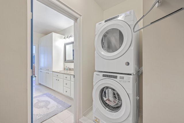 laundry area featuring sink, stacked washer / dryer, and light tile patterned flooring