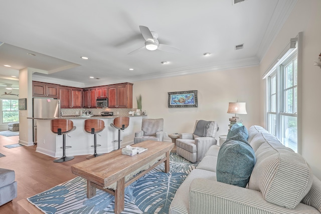 living room with ceiling fan, light hardwood / wood-style floors, and crown molding