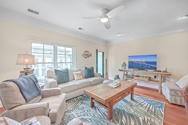 living room with light hardwood / wood-style floors, ornamental molding, and ceiling fan