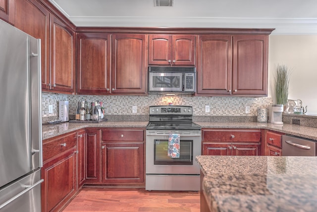 kitchen with stainless steel appliances, tasteful backsplash, light wood-type flooring, dark stone countertops, and ornamental molding