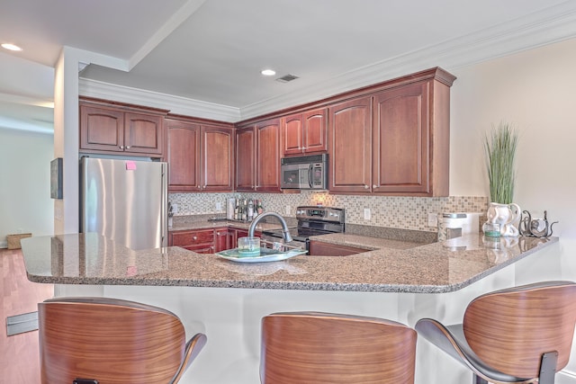 kitchen with kitchen peninsula, stone counters, and stainless steel appliances