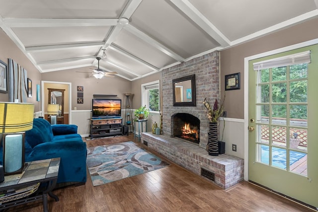 living room featuring a fireplace, vaulted ceiling with beams, a wealth of natural light, and hardwood / wood-style flooring